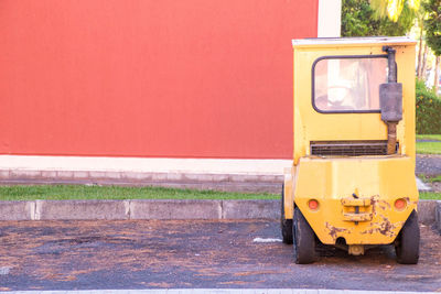 Yellow car on road against wall