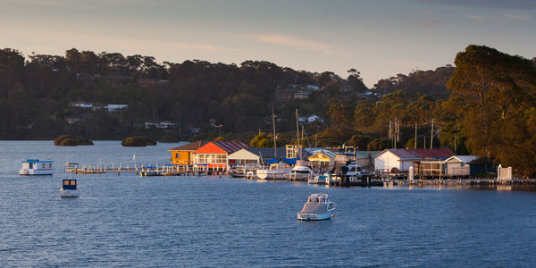 Sailboats in sea by buildings against sky