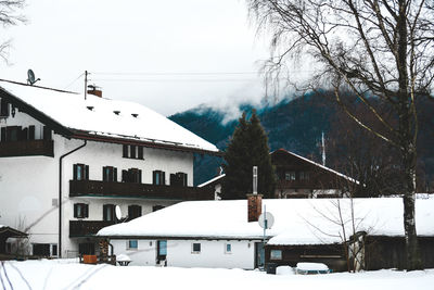 Snow covered houses by buildings against sky