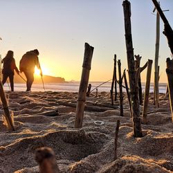 People on beach against sky during sunset