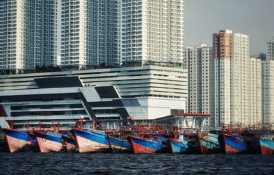 Boats moored in river by buildings in city