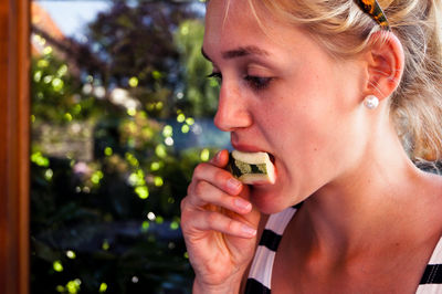 Close-up of young woman eating watermelon slice at home