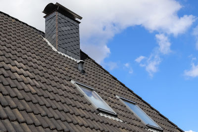 Roof window in velux style with black roof tiles