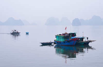 Fishing boats in sea against sky