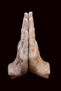 Cropped image of hands clasped against black background