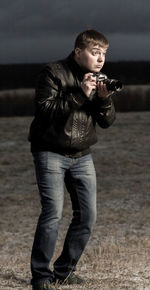 Man photographing with camera while standing on land at dusk