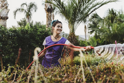 Smiling female garden center owner watering plants