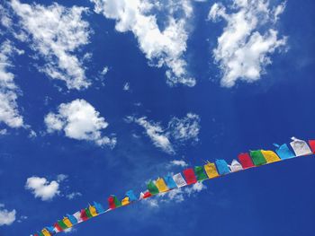 Low angle view of colorful prayer flags against blue sky