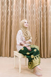 Young woman sitting on sofa at home