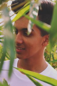 Close-up portrait of smiling young woman against plants