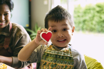 Portrait of son holding heart shape by mother