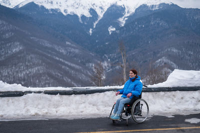 Rear view of man riding bicycle on snowcapped mountain