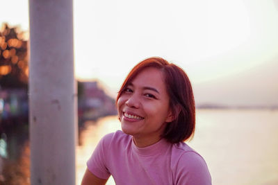 Portrait of smiling young woman against sky