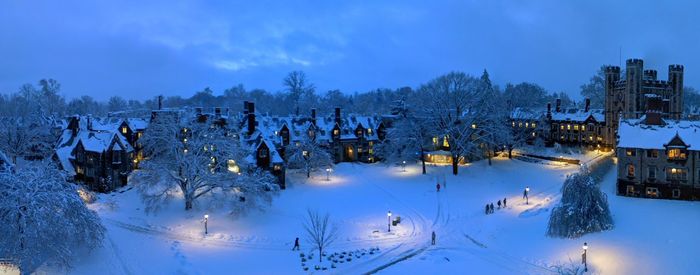 Panoramic view of snow covered field and houses against sky