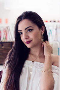 Close-up of young woman trying earring while standing in store