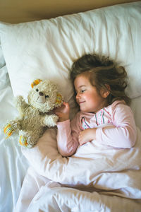 Girl lying on bed with stuffed toy at home