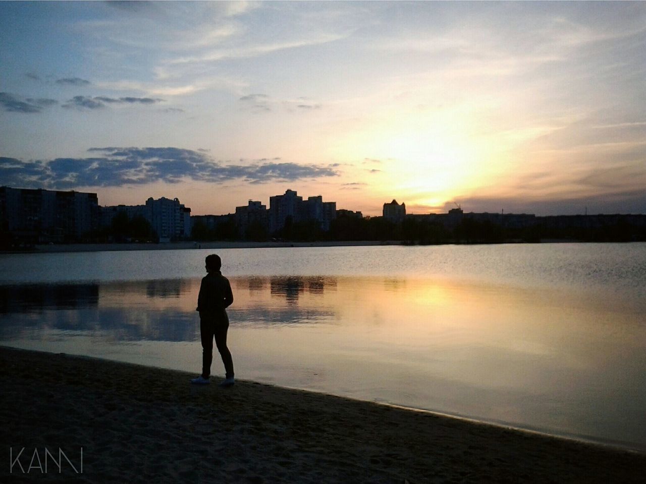 water, building exterior, sunset, architecture, built structure, sky, city, standing, silhouette, full length, lifestyles, reflection, rear view, leisure activity, river, lake, men, cityscape