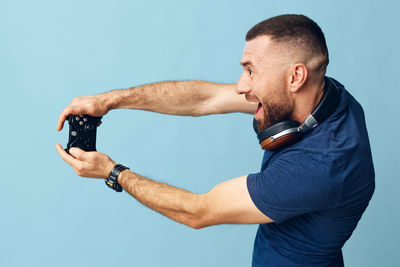 Side view of man photographing against blue background