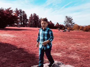 Full length of boy standing on field against sky