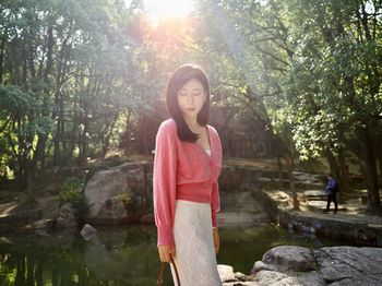 Portrait of young woman standing against waterfall