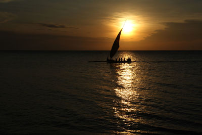 Silhouette sailboat in sea against sky during sunset