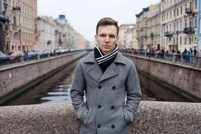 One handsome young man in winter or autumn coat standing next to river