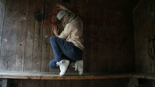 Full length of man sitting on seat against wall