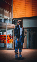 Full length of woman standing against brick wall