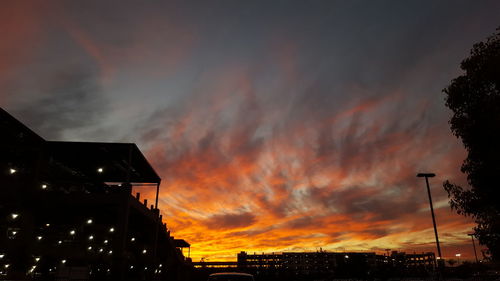 High section of illuminated buildings against cloudy sky during sunset