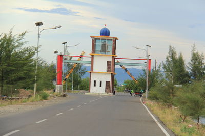 Empty road by building against sky