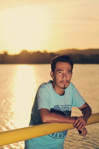 Portrait of man standing against sea at sunset