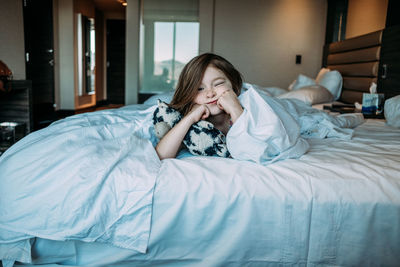 Center image of young child laying on bed with her stuffed cow