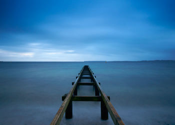 Pier over sea against blue sky