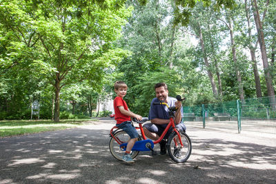Portrait of father and son with bicycle at park