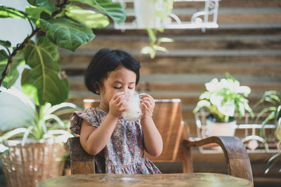 Portrait of girl drinking glass on table