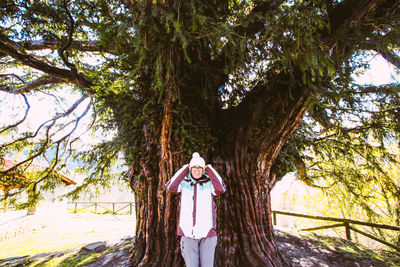 Woman standing by tree trunk