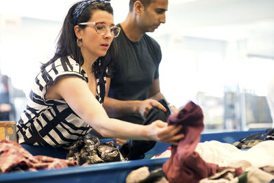 Serious volunteers checking clothes on conveyor belt at workshop