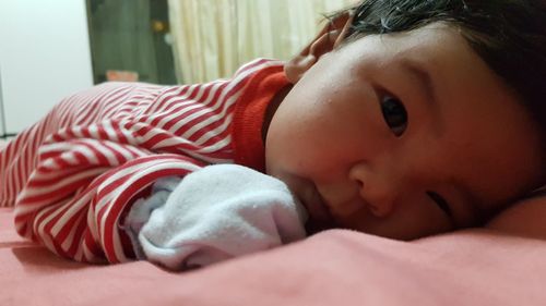 Close-up portrait of cute baby lying on bed