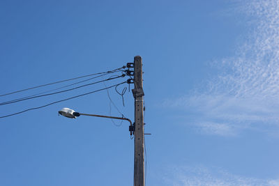 Low angle view of electricity pylon against blue sky