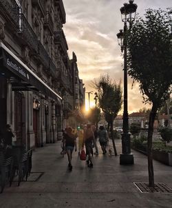 People walking on city street against sky