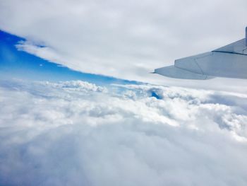 Close-up of airplane wing against cloudy sky