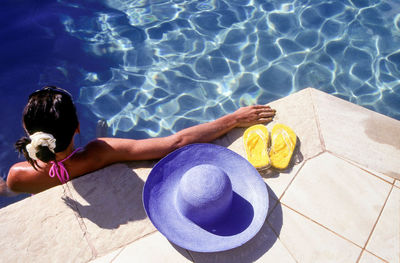 High angle view of woman with hat and slippers relaxing in swimming pool