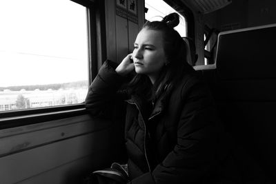 Young woman looking through window