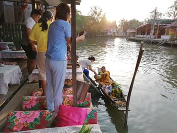 Rear view of people at boats in canal