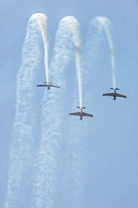 Low angle view of military airplanes performing airshow against sky