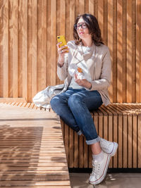 Mindful woman is texting on smartphone while eating tasty pastry. reading news or  social media. 