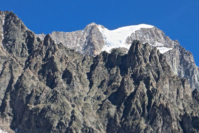 Low angle view of rocky mountains against clear blue sky