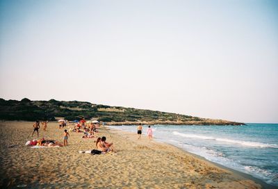 People on beach against clear sky
