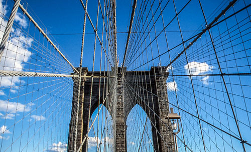 Low angle view of suspension bridge against blue sky