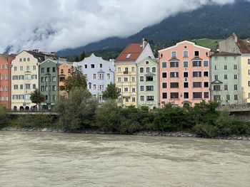 Buildings by river against sky